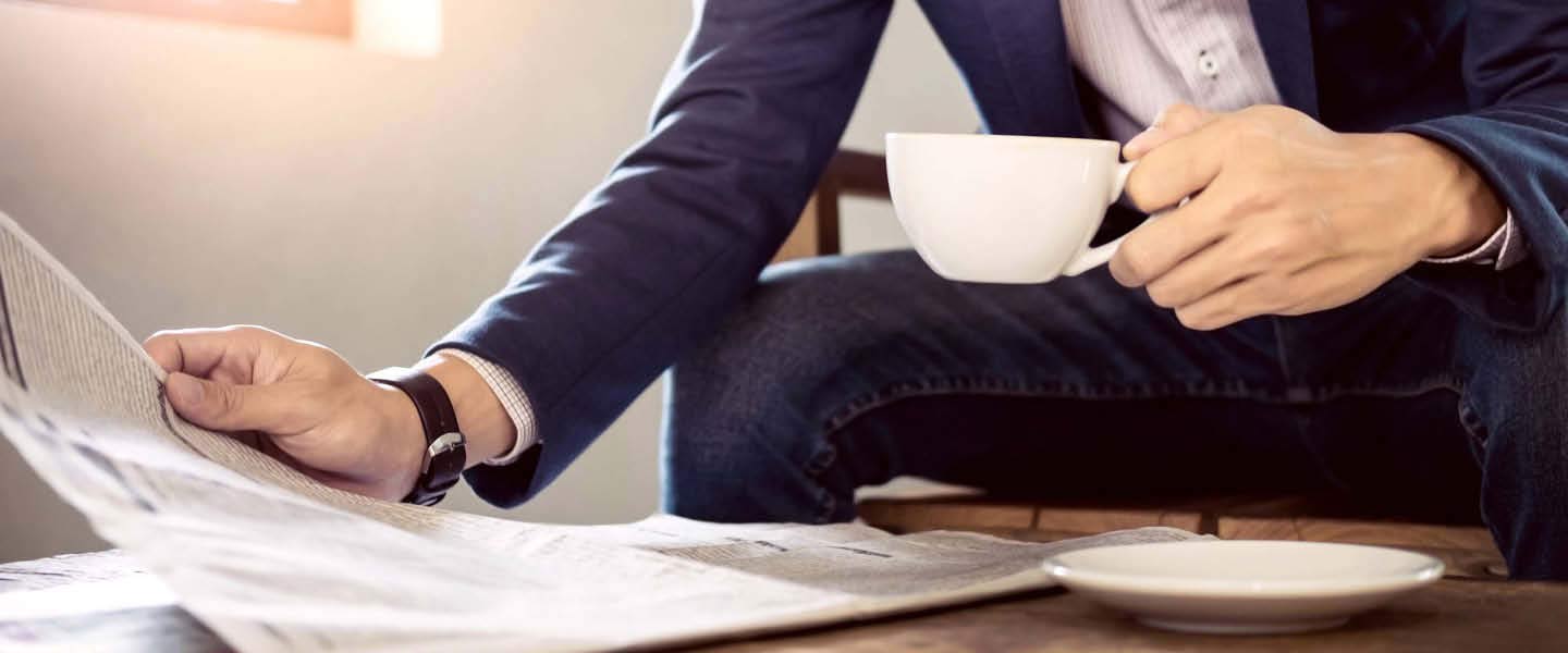 Picture of a businessman with a cup of coffee reading a newspaper