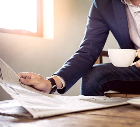 Picture of a businessman with a cup of coffee reading a newspaper